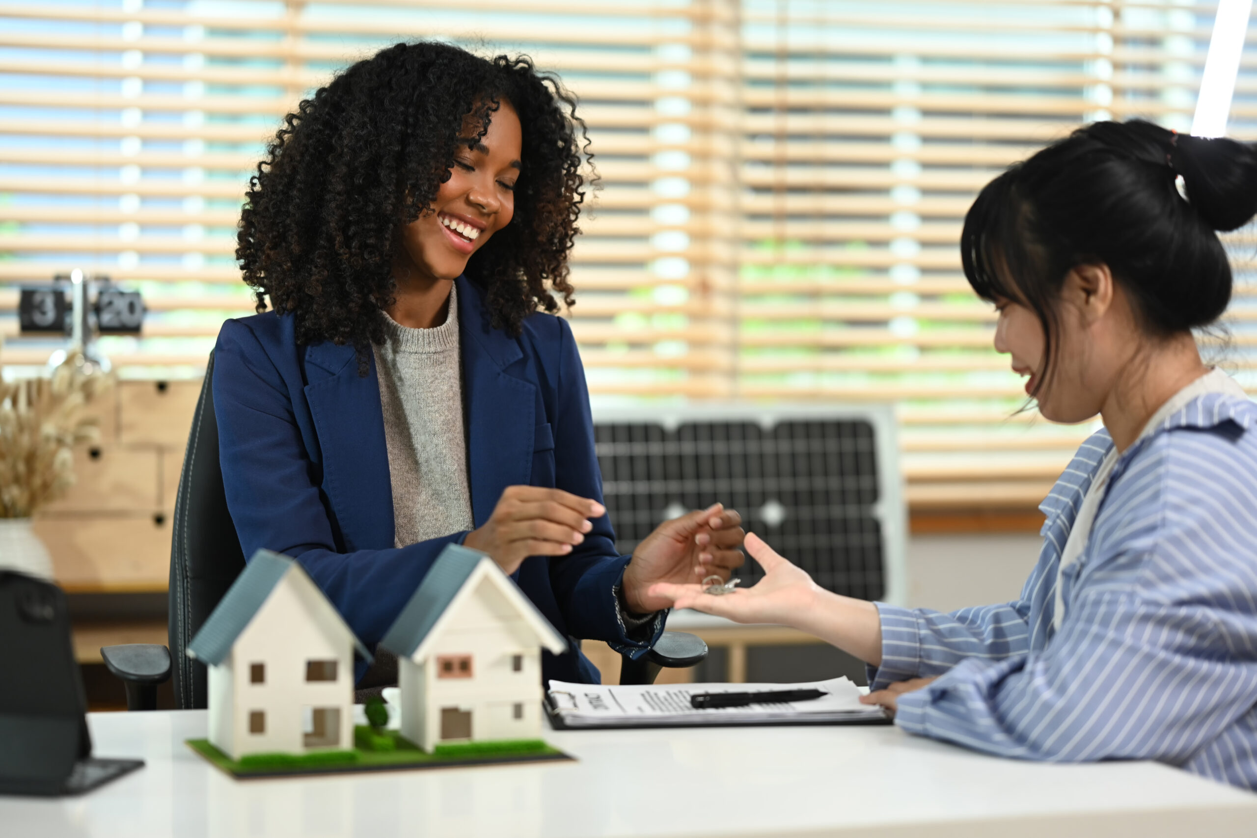 Smiling black lady giving house keys to to new Buy-To-Let property owner
